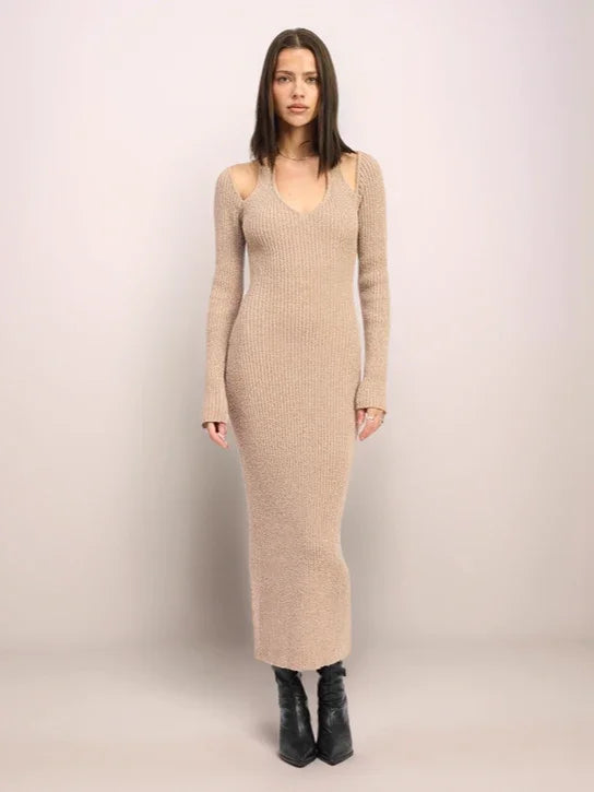 Woman wearing a beige ribbed dress against a plain background