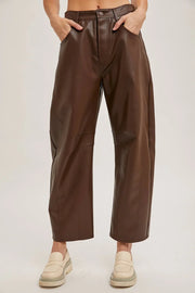 Person wearing brown leather pants on a plain background