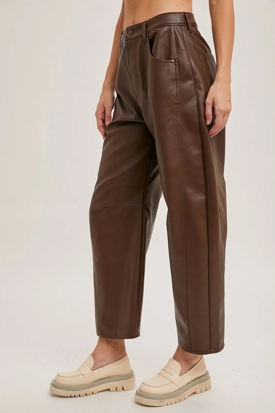 Brown leather pants worn by a person on a plain background