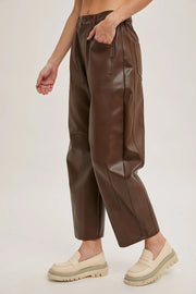 Brown leather pants worn by a person on a plain background
