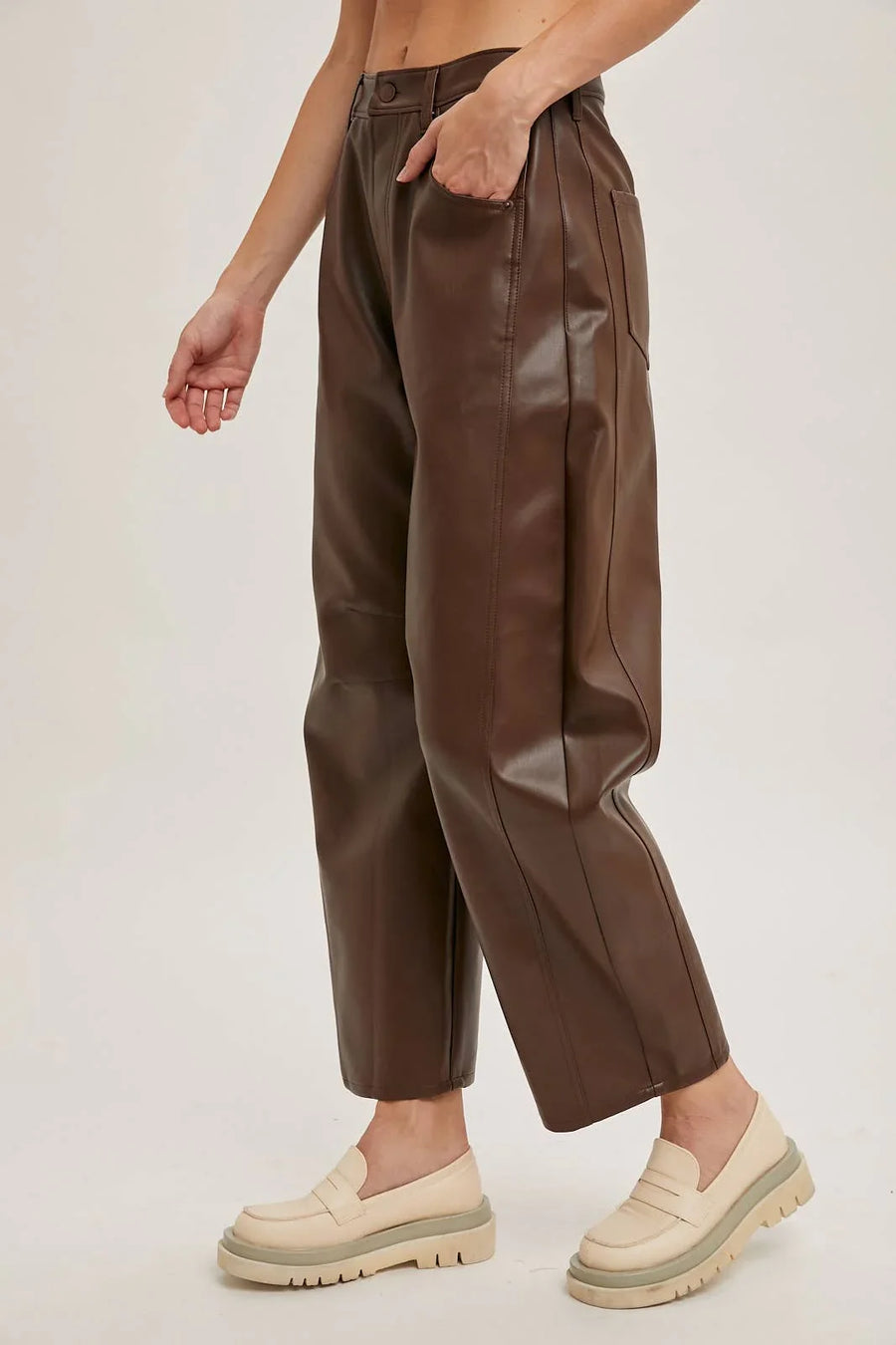 Brown leather pants worn by a person on a plain background