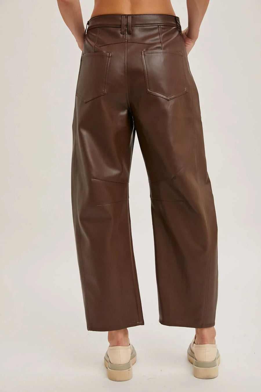 Brown leather pants worn by a person on a plain background