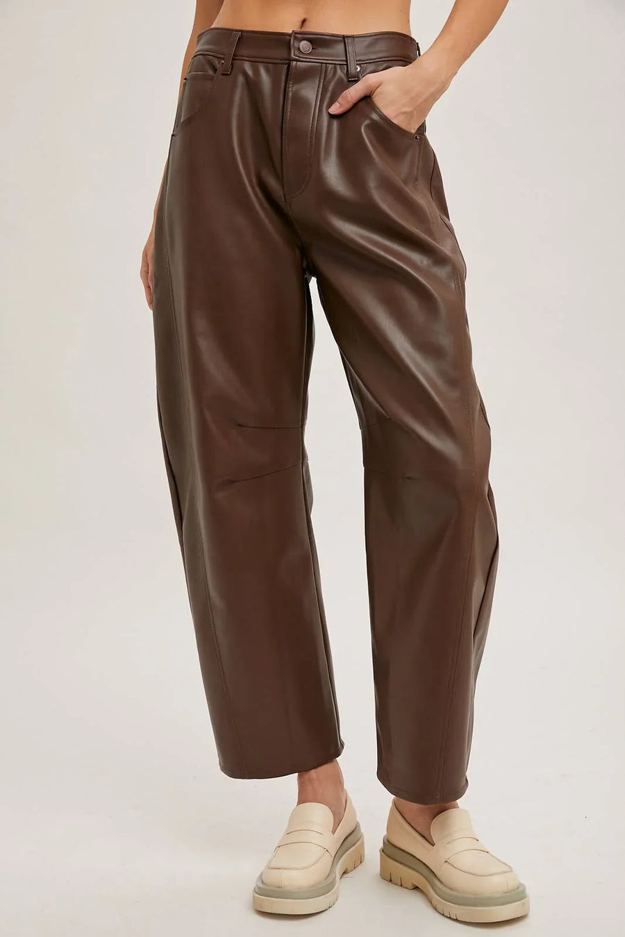 Brown leather pants worn by a person on a plain background
