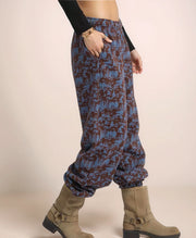 Person wearing blue patterned pants and brown boots on a beige background