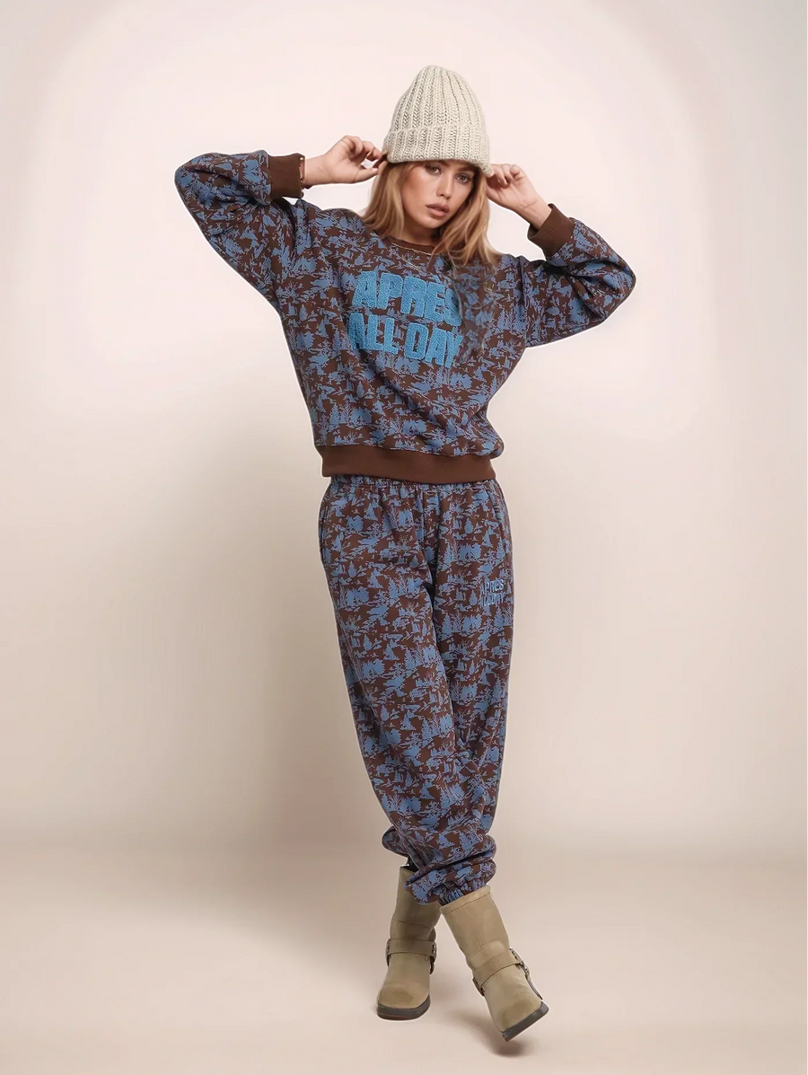 Person wearing a patterned sweater and pants with a beanie on a plain background