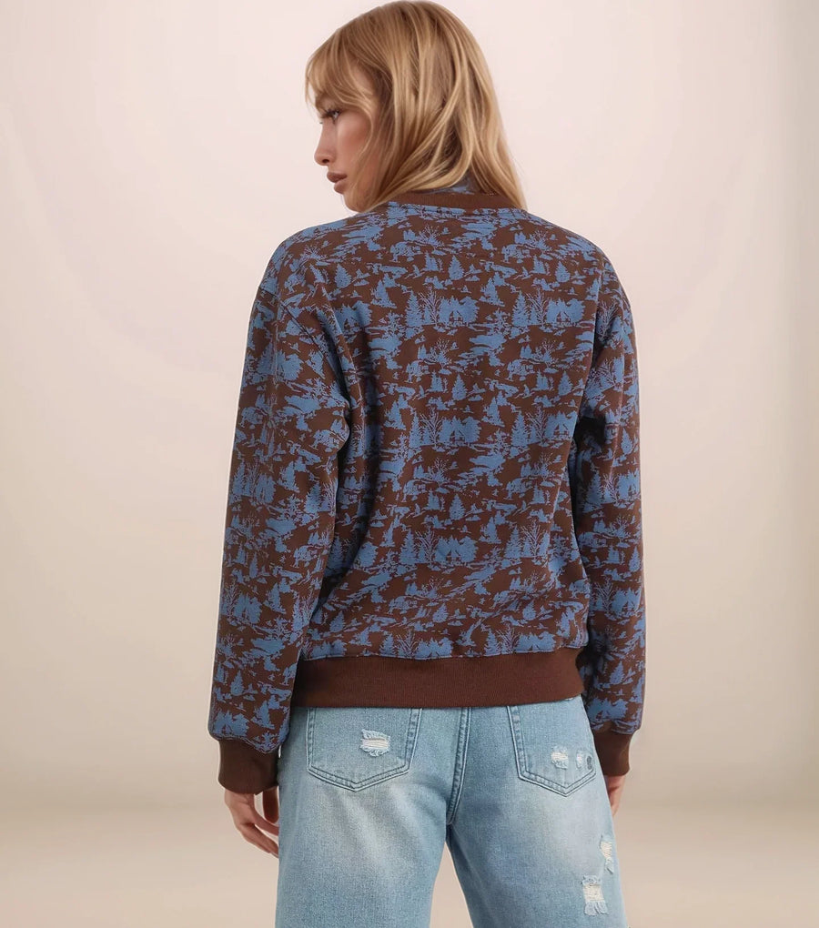 Person wearing a patterned jacket and denim shorts on a plain background