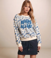 Woman wearing a patterned sweater with 'APRES ALL DAY' text on a beige background