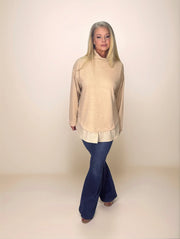 a blonde woman in a layered turtleneck sweater with a pinstripe shirt hem and dark blue jeans.
