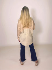 a blonde woman is facing away from the camera in a layered sweater that has a button up shirt hem in the back.