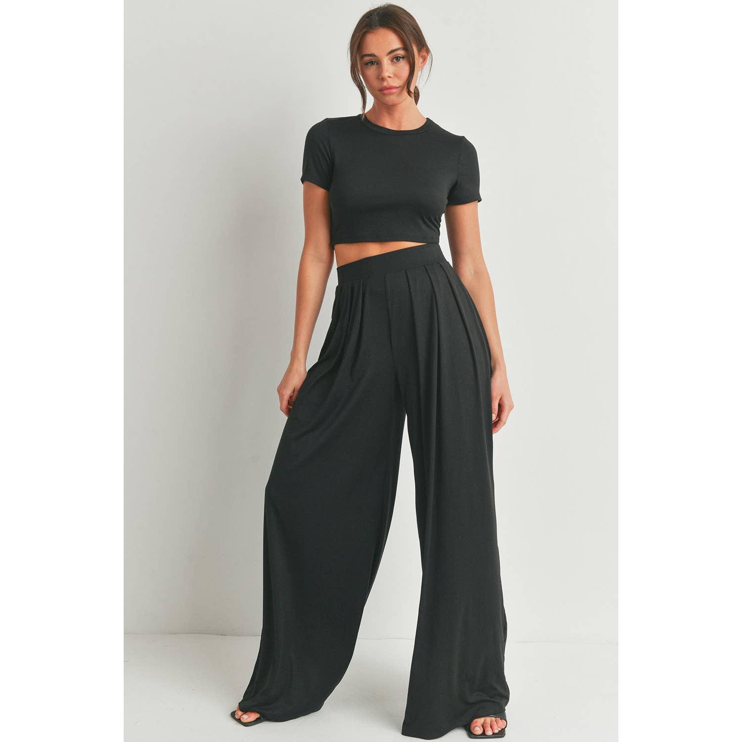 a brunette women modeling a pair of black knit palazzo pants and a black short sleeve cropped t-shirt