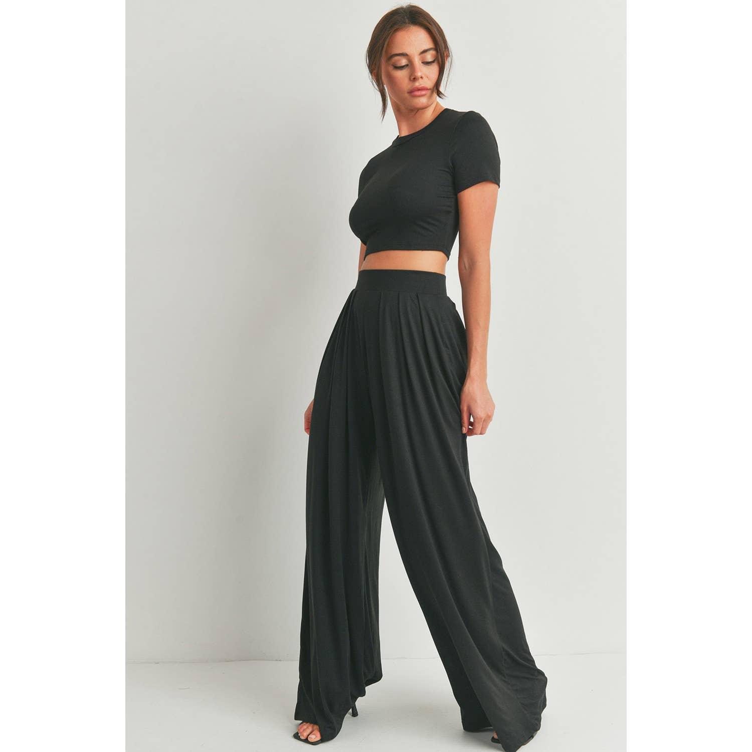 a brunette women modeling a pair of black knit palazzo pants and a black short sleeve cropped t-shirt