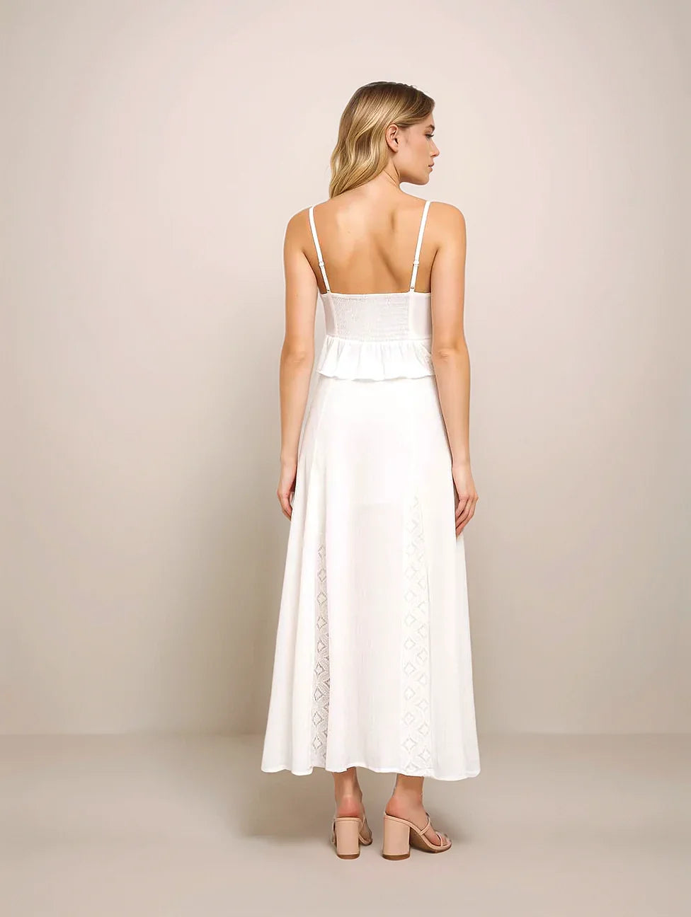Woman wearing a white dress with thin straps on a beige background