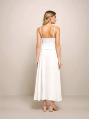 Woman wearing a white dress with thin straps on a beige background