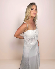 a blonde woman is wearing a bohemian inspired white camisole and maxi skirt that has diamond pattern lace panels on the skirt and sides of camisole.