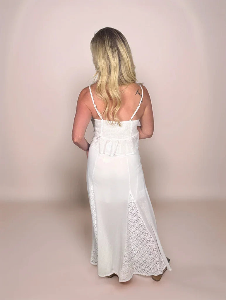 a blonde woman is facing backwards and is wearing a matching camisole with a smocked back and adjustable straps and a maxi skirt with diamond lace triangular inserts.