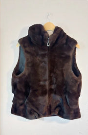 Brown fur vest on a hanger against a white wall