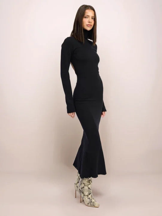 Woman wearing a black dress with a flared skirt on a plain background