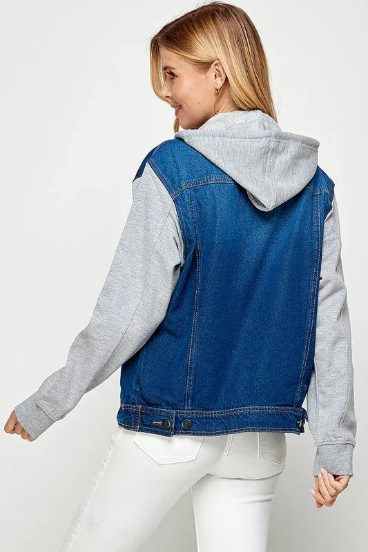 Person wearing a dark blue denim vest over a gray hoodie on a white background