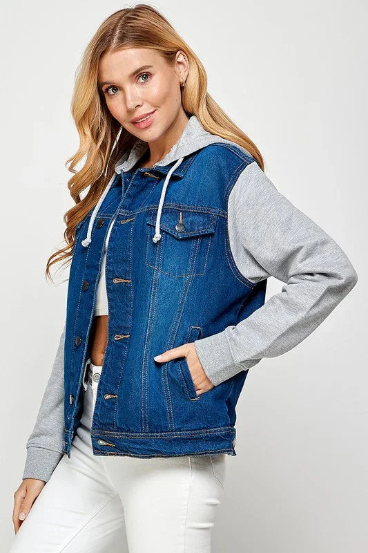 Woman wearing a dark wash denim vest over a gray hoodie on a white background