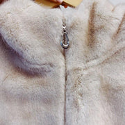 Close-up of a fur coat with a silver zipper and a hand holding a yellow object.
