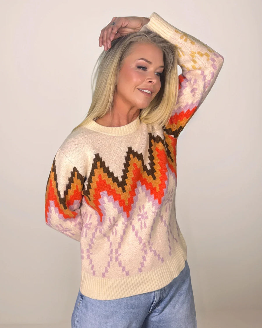 Person wearing a colorful patterned sweater with a plain background