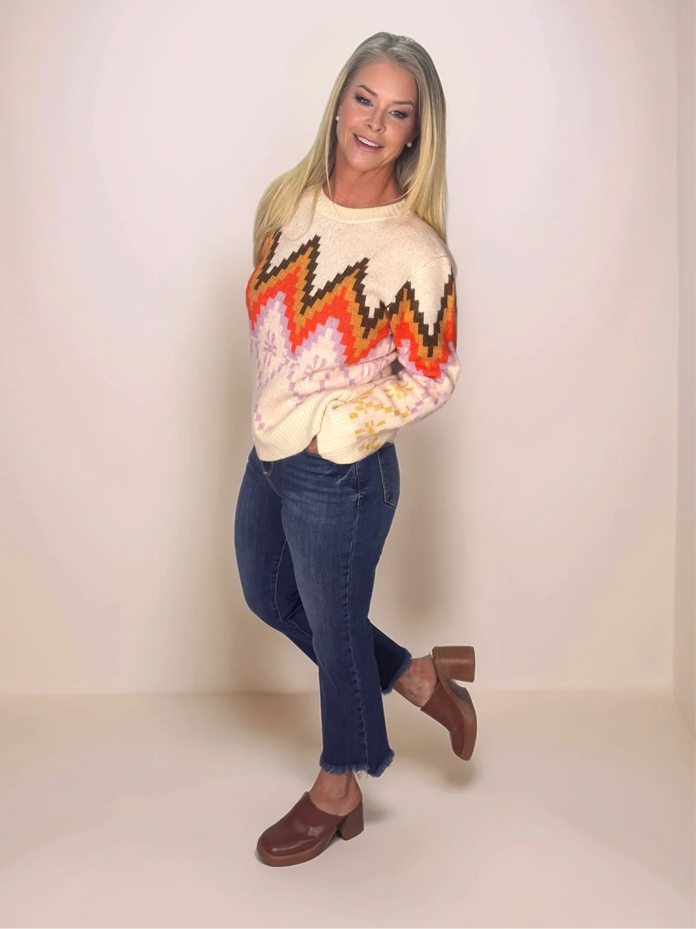 Woman wearing a colorful sweater with a zigzag pattern on a plain background