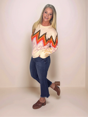 Woman wearing a colorful sweater with a zigzag pattern on a plain background