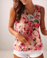 a woman with brown hair is wearing a floral tank top with a round neckline and white jean shorts