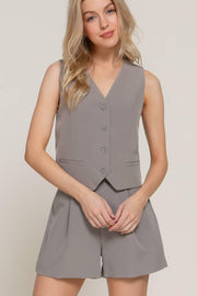 a blonde woman in a pair of gray pleated tailored shorts with a matching vest.