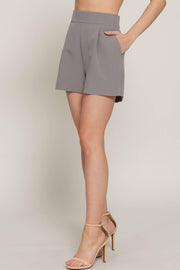 a pair of gray pleated tailored shorts on a woman from the waist down