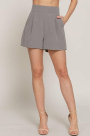a pair of gray pleated tailored shorts on a woman from the waist down