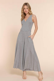 a blonde woman modeling a gray knit surplice jumpsuit. It has wide legs and she has one hand in her pocket.