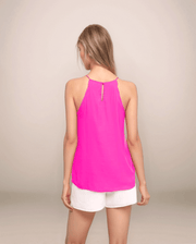 a blonde woman is facing backwards wearing white shorts with a hot pink halter style tank that has a keyhole button closure in the back and scallop trim detail at the armholes.