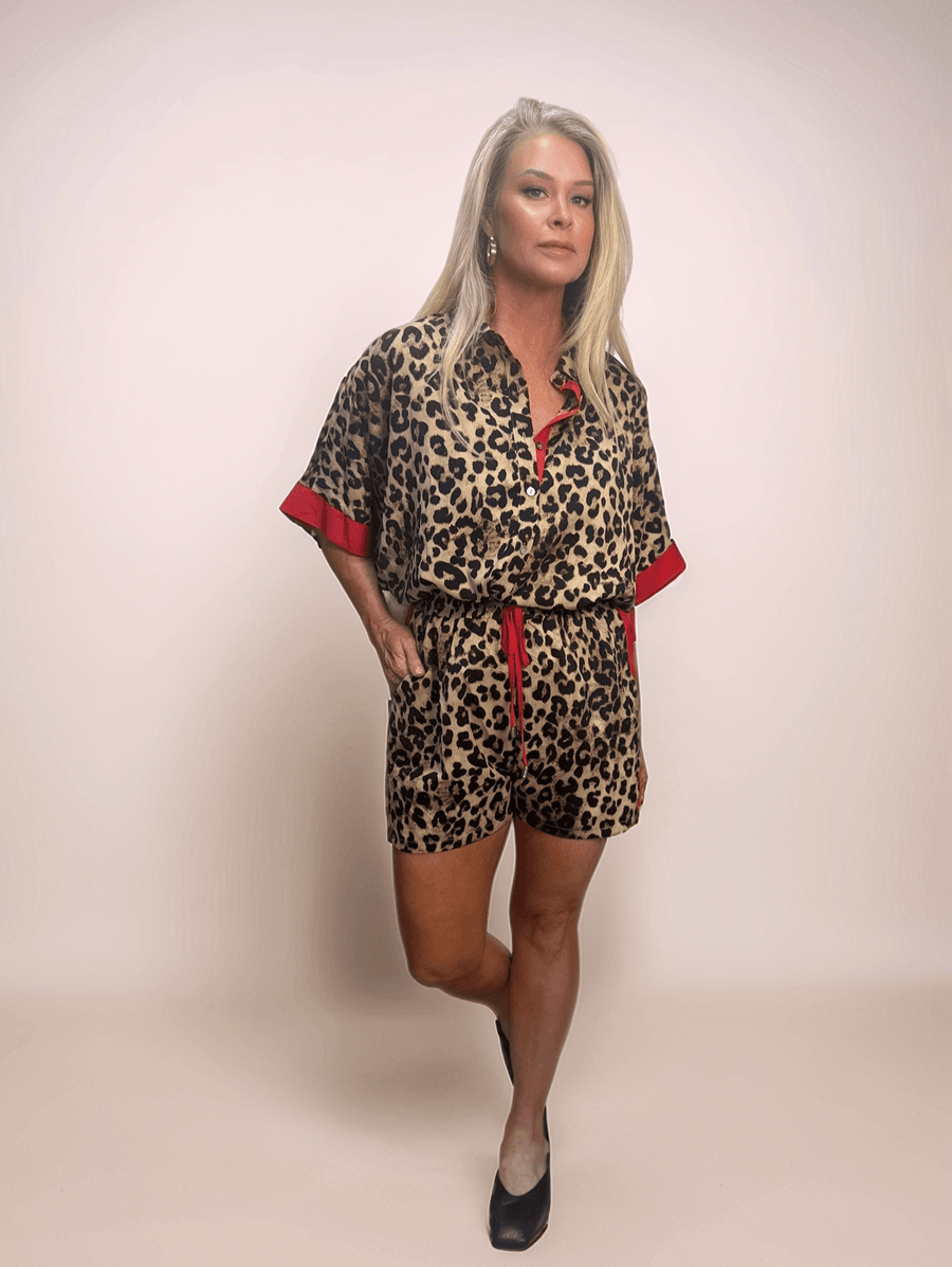 Fashionable blonde woman modeling a comfortable and chic leopard print shorts and button down shirt set featuring red contrasting details, perfect for a casual yet trendy look.