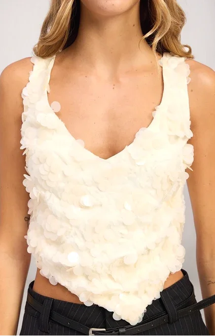 White ruffled top worn by a person on a plain background