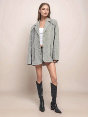 Woman wearing a gray coat and black knee-high boots on a beige background