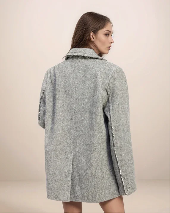 Woman wearing a gray coat against a beige background