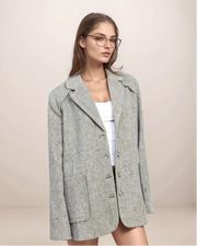 Woman wearing a gray blazer over a white top on a beige background