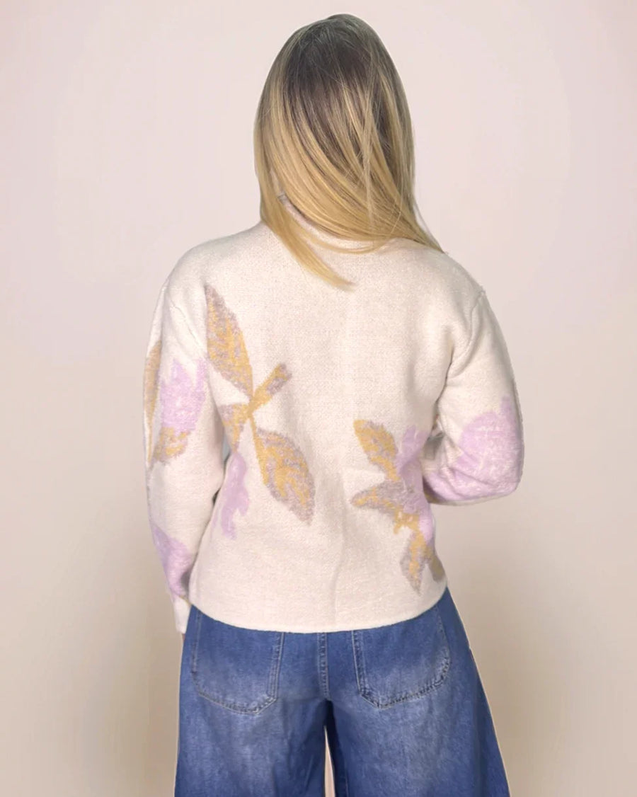 a blonde woman wearing a floral sweater and jeans is facing away from the camera