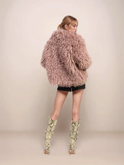 Person wearing a fluffy pink coat and patterned boots on a plain background
