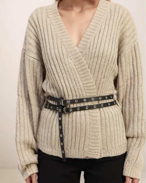 Beige ribbed sweater with a belt worn by a person on a plain background