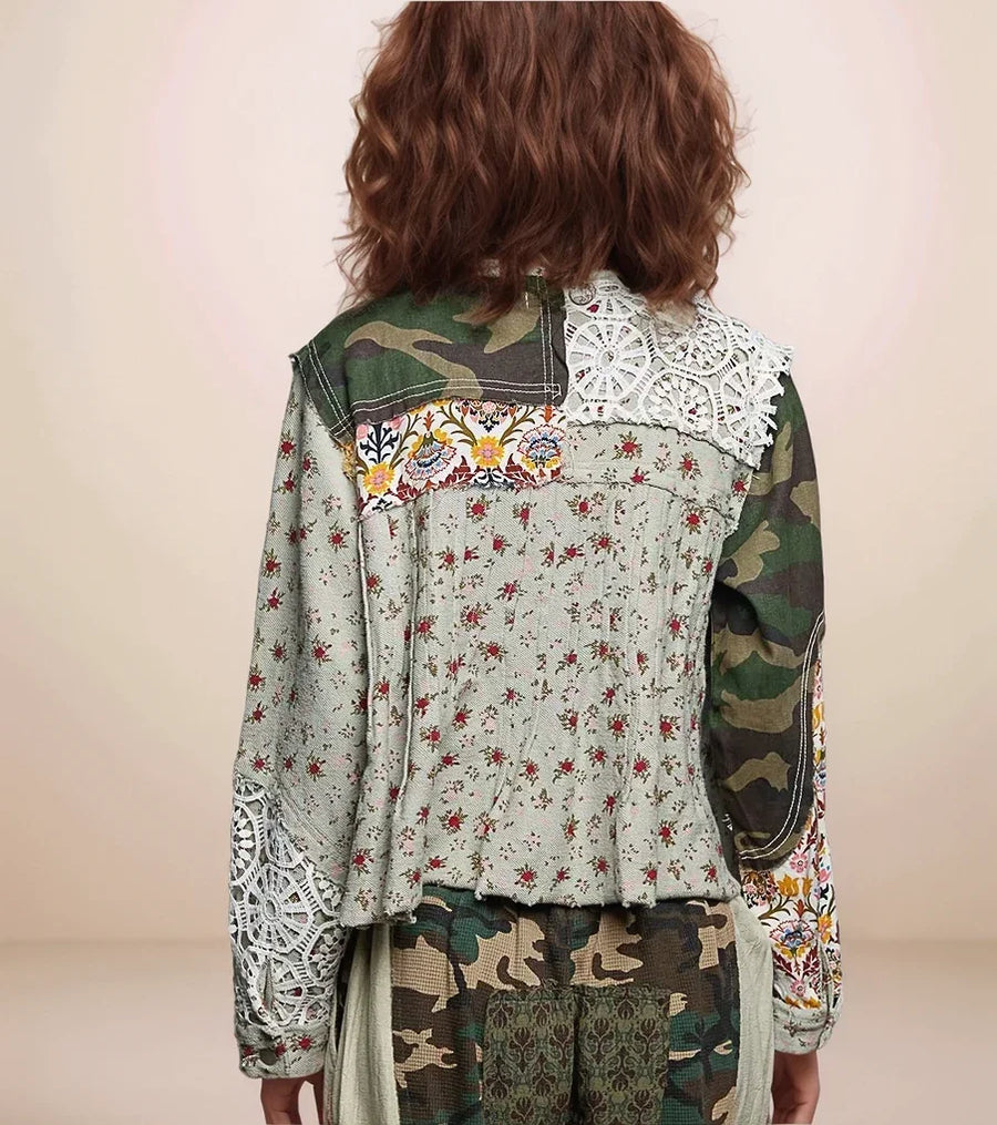 Person wearing a jacket with floral and camouflage patterns on a plain background