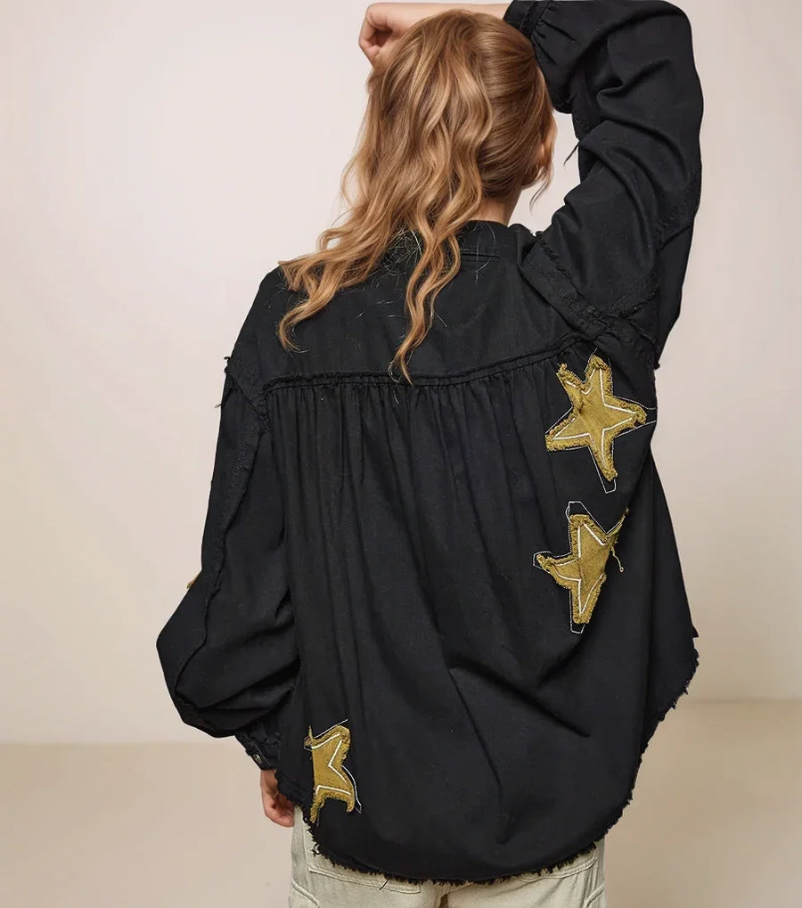 person wearing a black jacket with gold star patches on the back