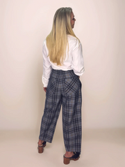 Person wearing plaid pants and a white shirt against a plain background