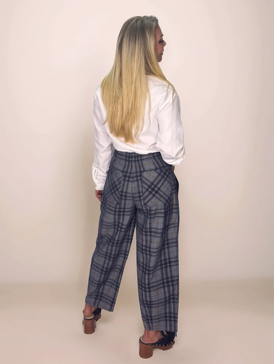 Person wearing plaid pants and a white shirt against a plain background