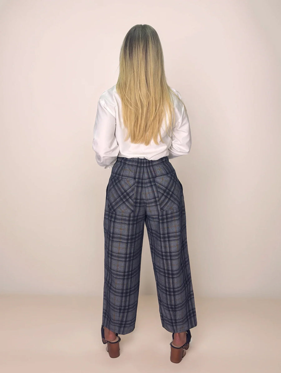 Person wearing a white shirt and plaid pants from behind on a plain background