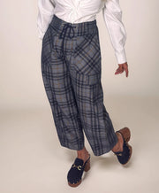 Person wearing blue plaid pants and a white shirt on a plain background