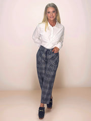 a blonde, stylish woman is wearing a white button up shirt and blue plaid pants.