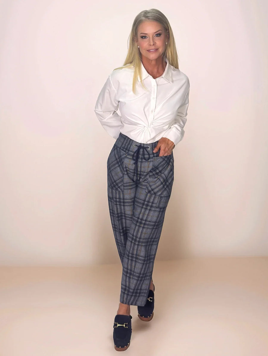 a blonde, stylish woman is wearing a white button up shirt and blue plaid pants.