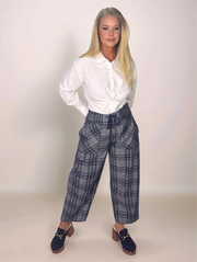 Woman wearing a white blouse and plaid pants against a plain background